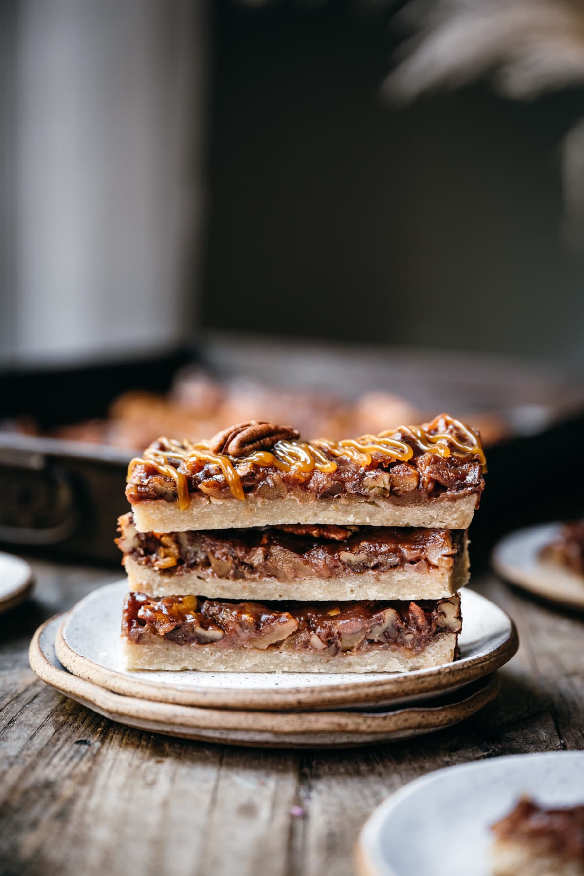 side view of stack of 3 vegan pecan pie bars on small white plate.