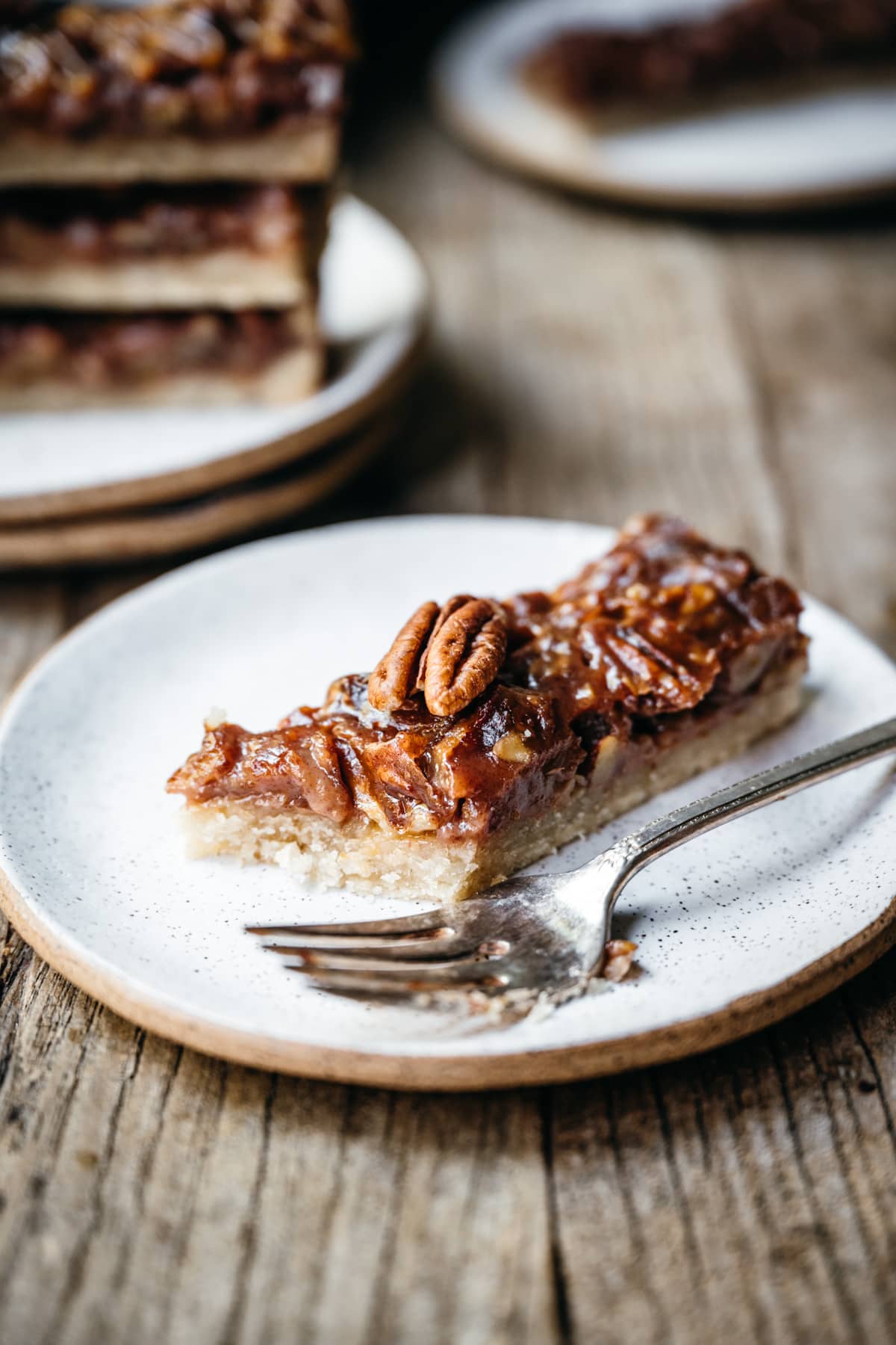 side view of vegan pecan pie caramel bar on a small plate. 