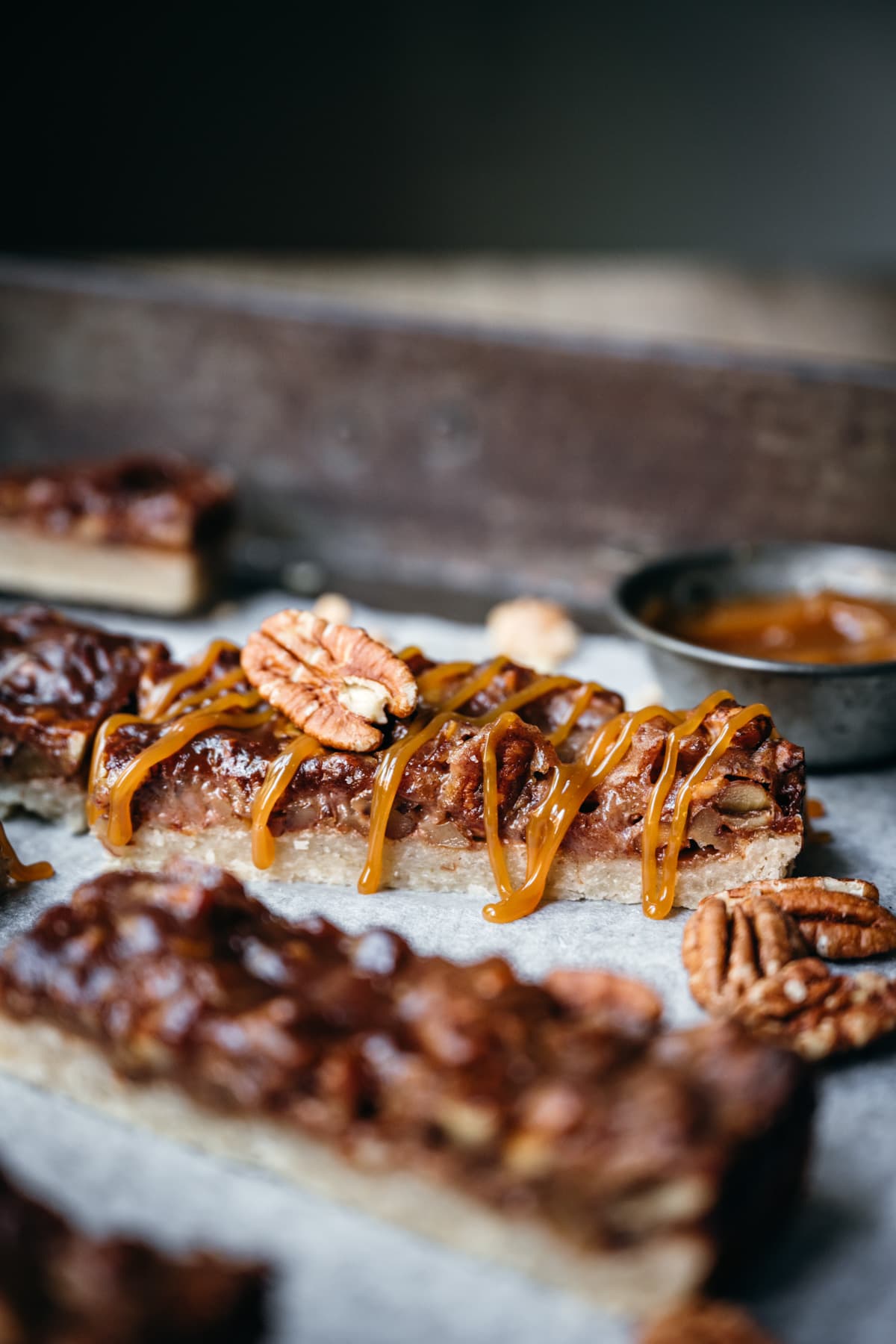 close up view of vegan pecan pie bar with caramel drizzle.