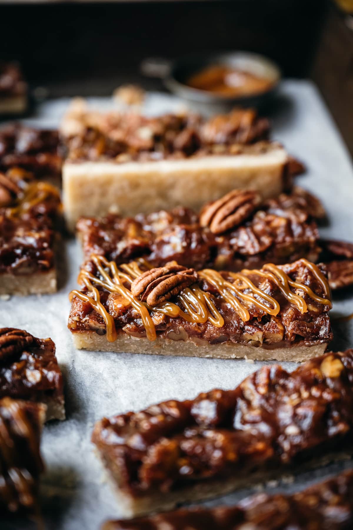 side view of vegan pecan pie bars with caramel topping. 