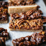 side view of vegan pecan pie bars with caramel topping.