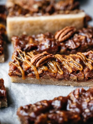 side view of vegan pecan pie bars with caramel topping.