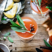 overhead view of cranberry orange mimosas garnished with fresh sage.