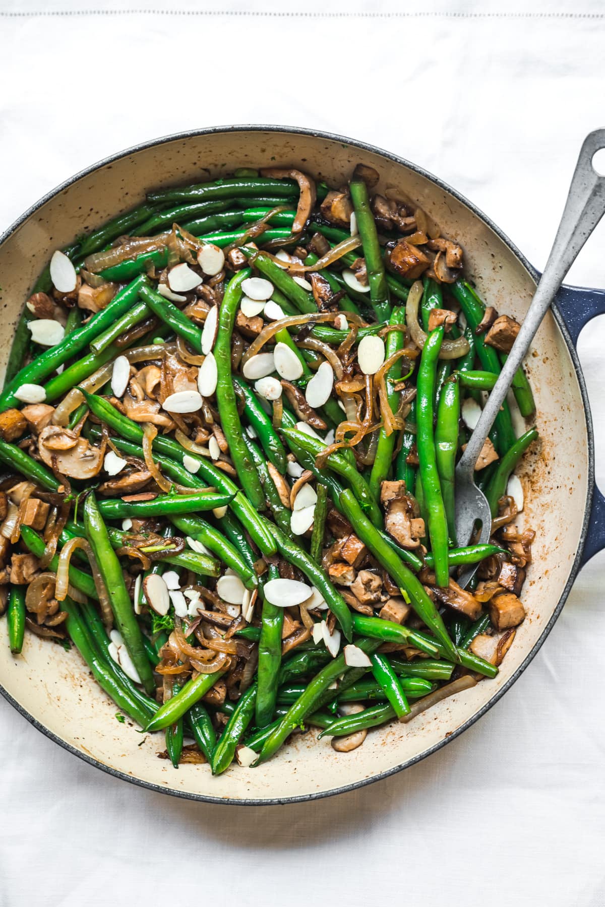 overhead view of vegan green beans with tofu bacon, mushrooms and caramelized onions in pan.