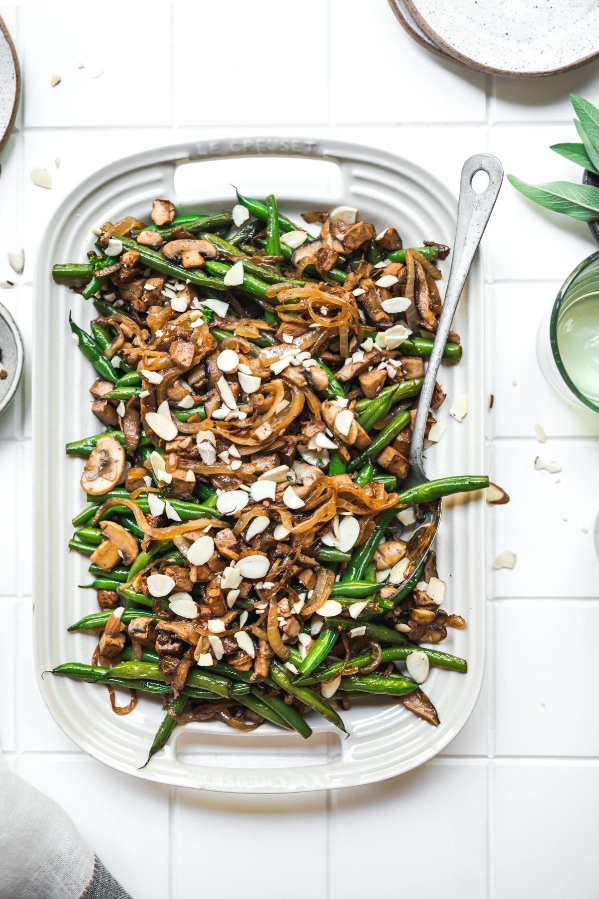 overhead view of vegan green beans with tofu bacon, mushrooms and caramelized onions on white platter.