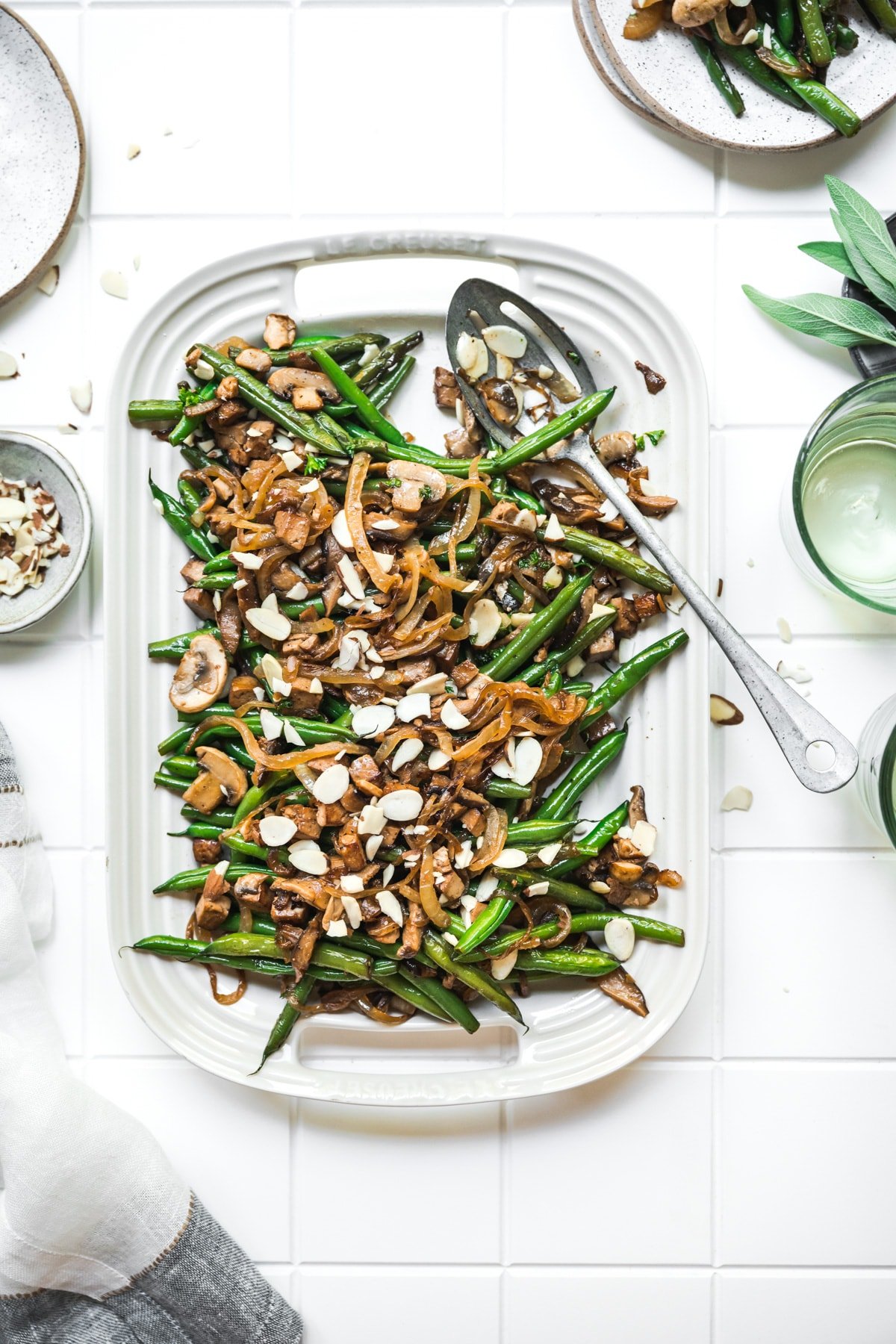 overhead view of vegan green beans with tofu bacon, mushrooms and caramelized onions on white platter.