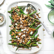 overhead view of vegan green beans with tofu bacon, mushrooms and caramelized onions on white platter.