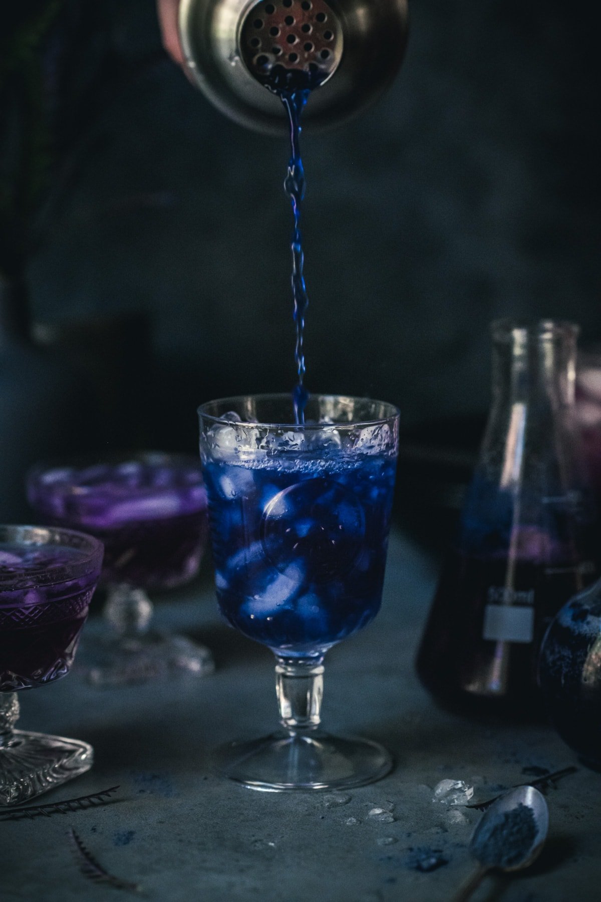 pouring blue butterfly pea tea into a cocktail glass