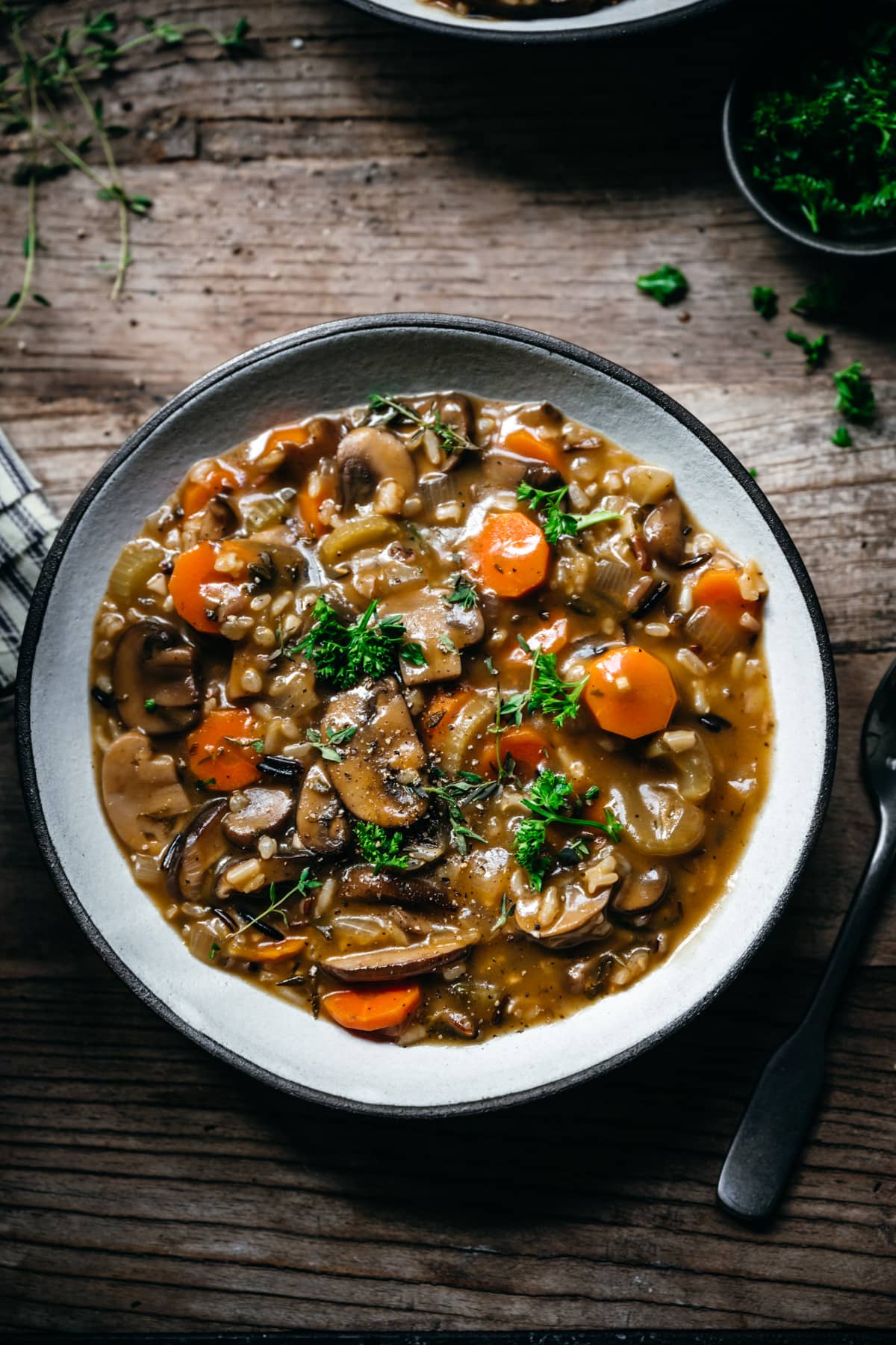 overhead view of vegan wild rice mushroom soup in a bowl on wood table. 