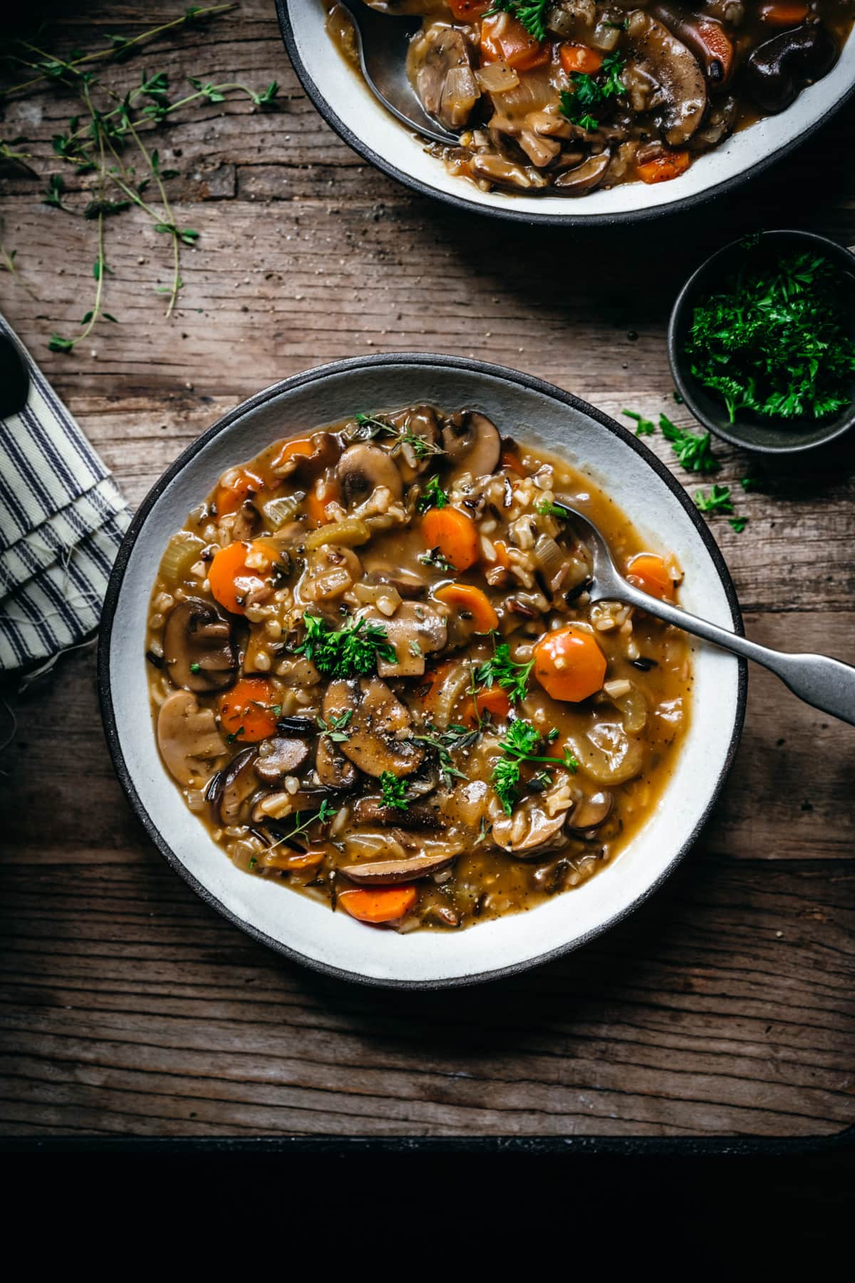 overhead view of vegan wild rice mushroom soup in a bowl on wood table. 