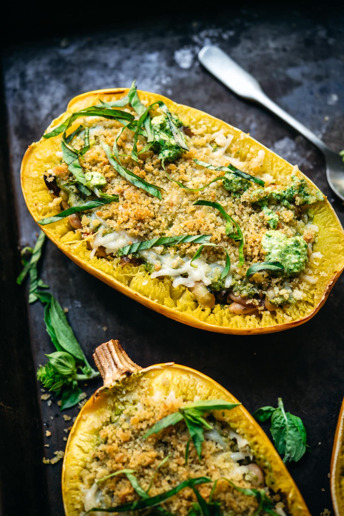 close up side view of spaghetti squash filled with pesto, white beans and topped with breadcrumbs.