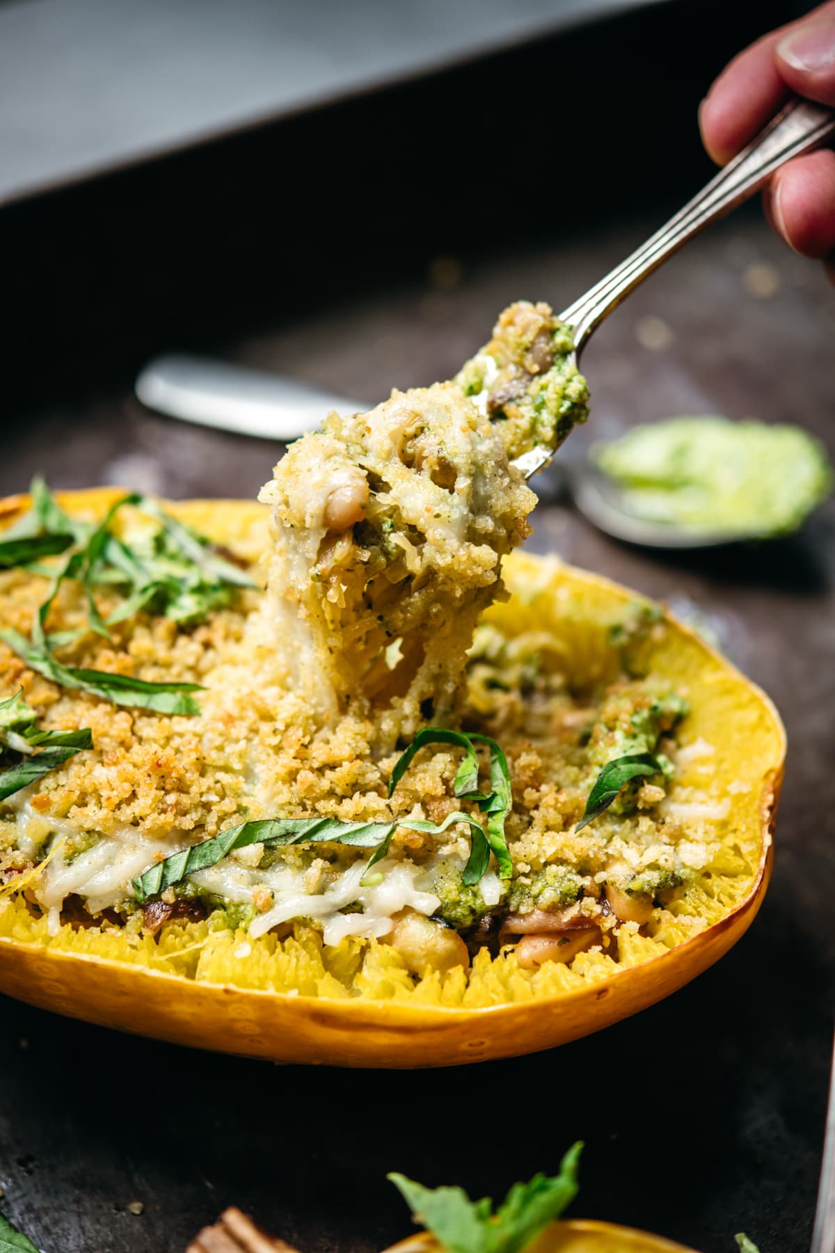 side view of pesto spaghetti squash boat with cheese and breadcrumbs with fork.