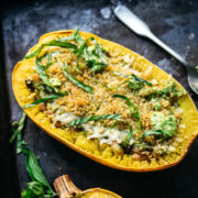 close up side view of spaghetti squash filled with pesto, white beans and topped with breadcrumbs.