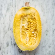 overhead view of spaghetti squash sliced in half on marble surface.