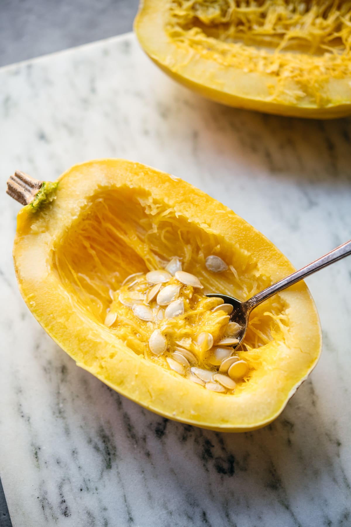 side view of scooping seeds out of spaghetti squash.