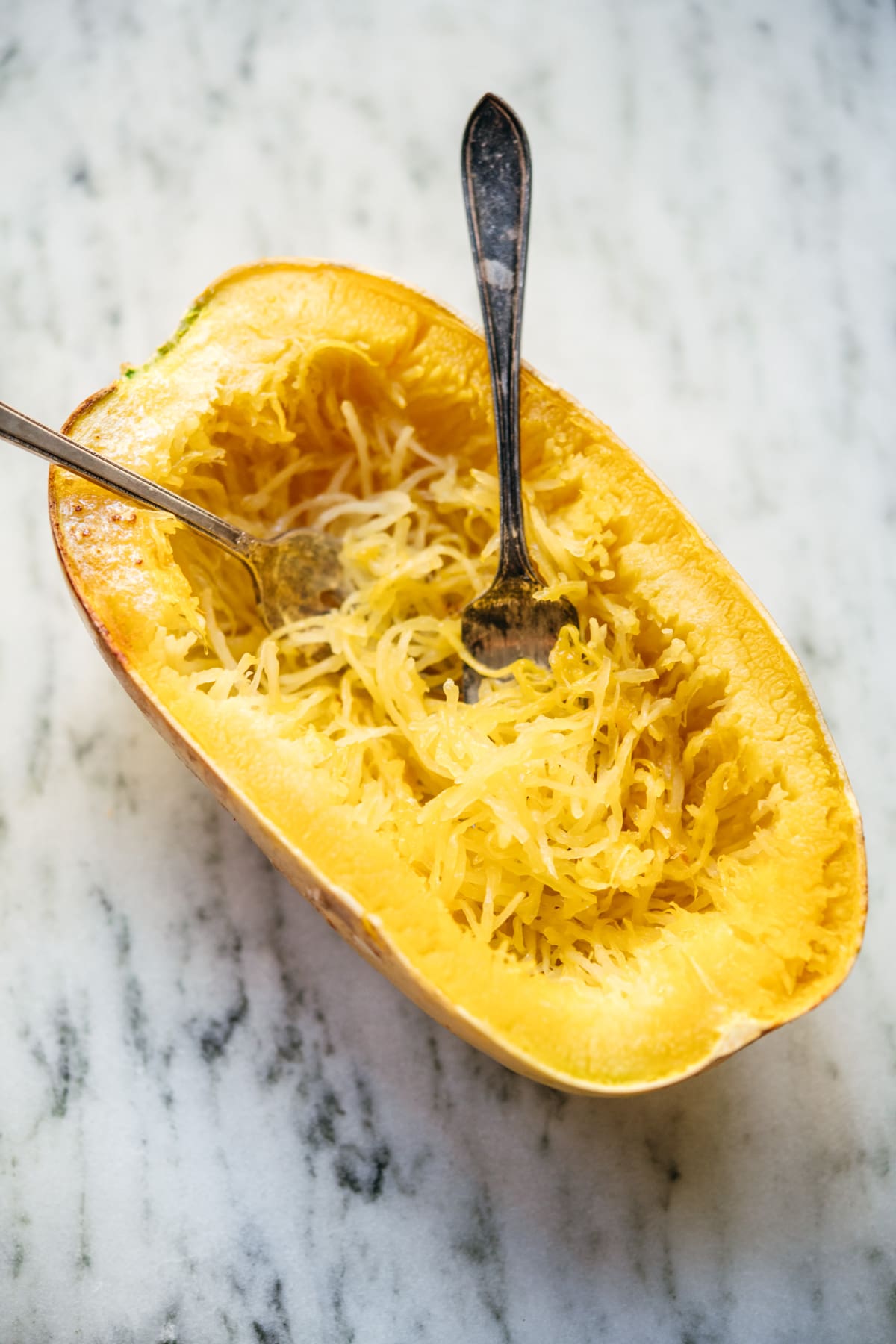 side view of two forks in a cooked, shredded spaghetti squash.