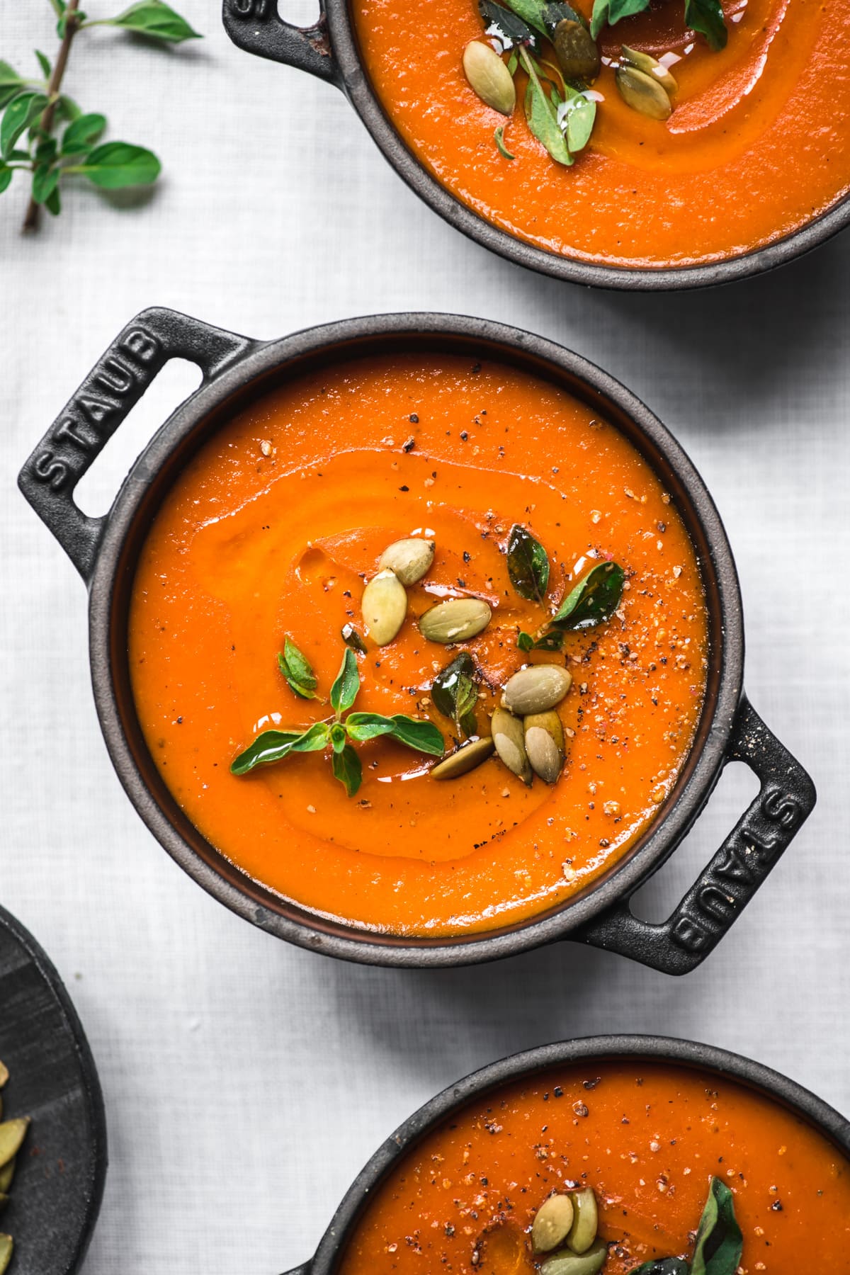 close up view of vegan roasted red pepper soup in black ramekins. 