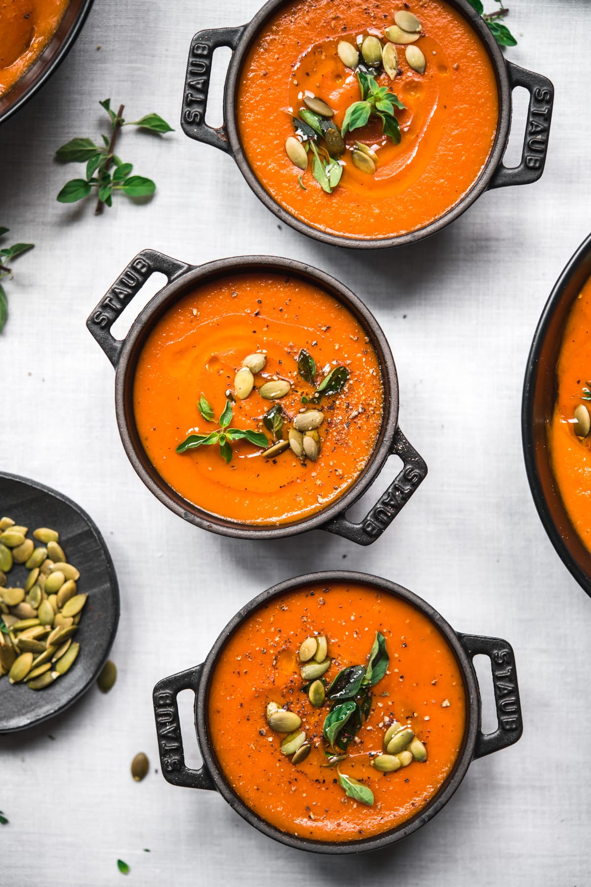 close up view of vegan roasted red pepper soup in black ramekins. 