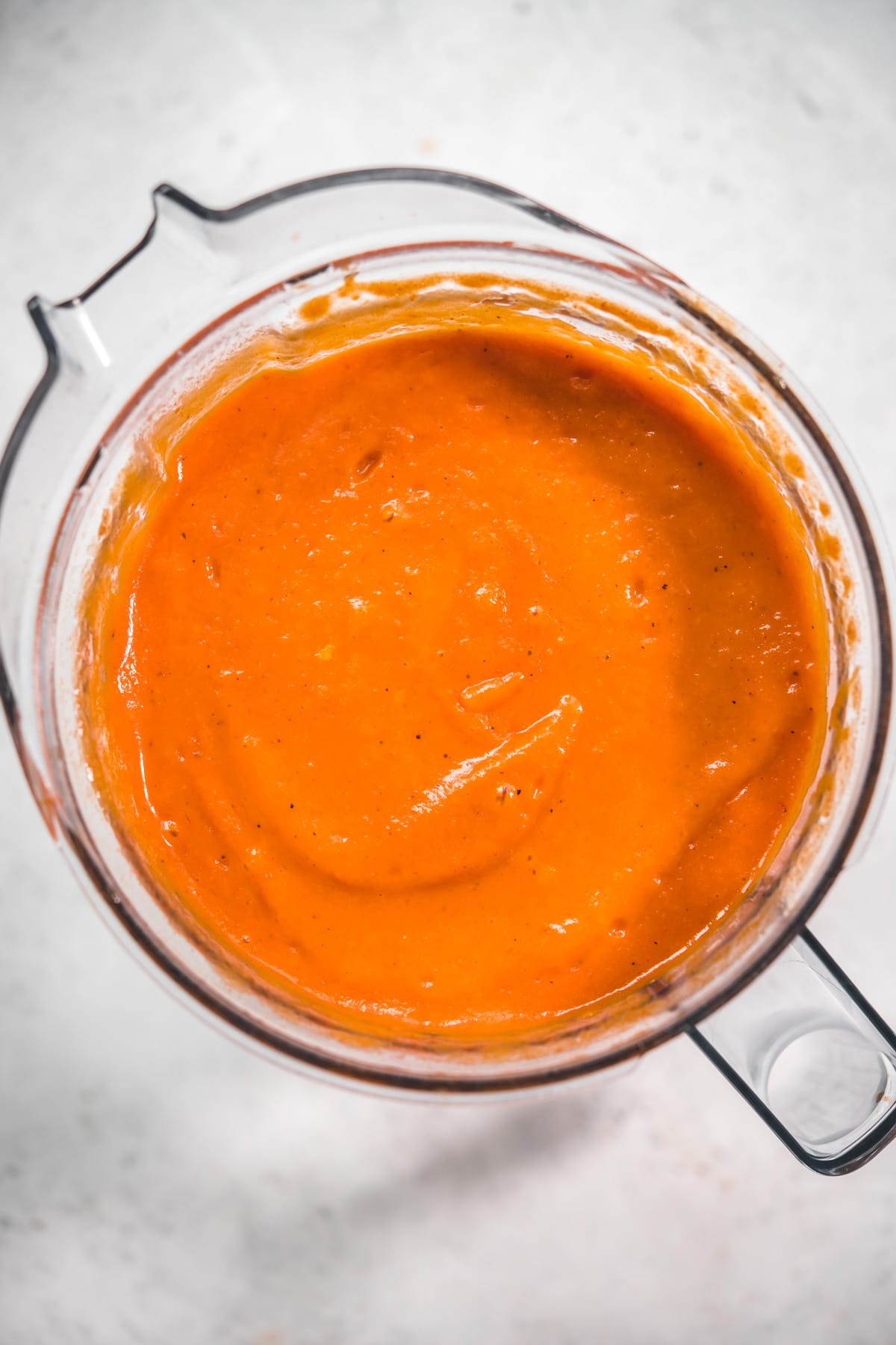 close up overhead view of creamy roasted red pepper soup in a blender.