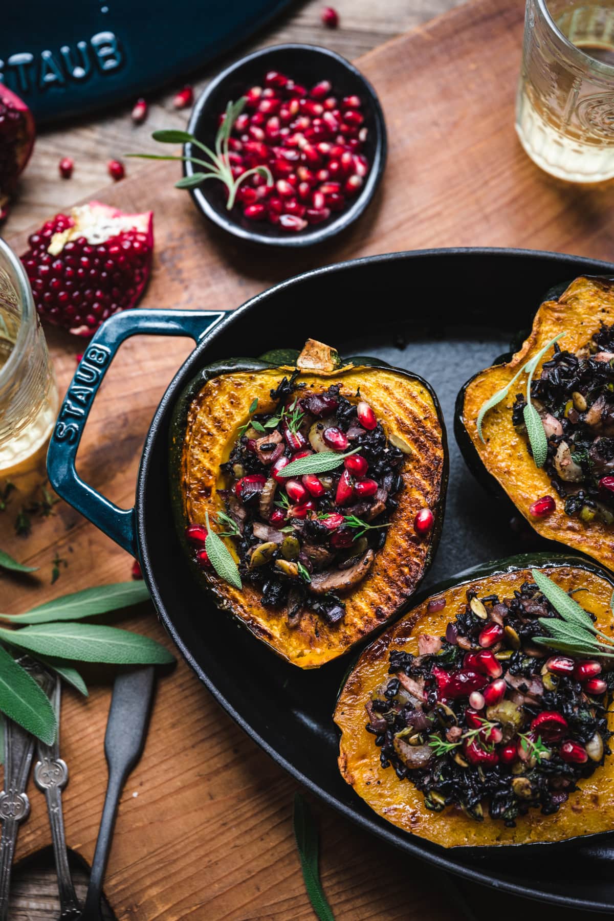 overhead view of vegan stuffed acorn squash with black rice, mushrooms and pomegranate seeds on top.