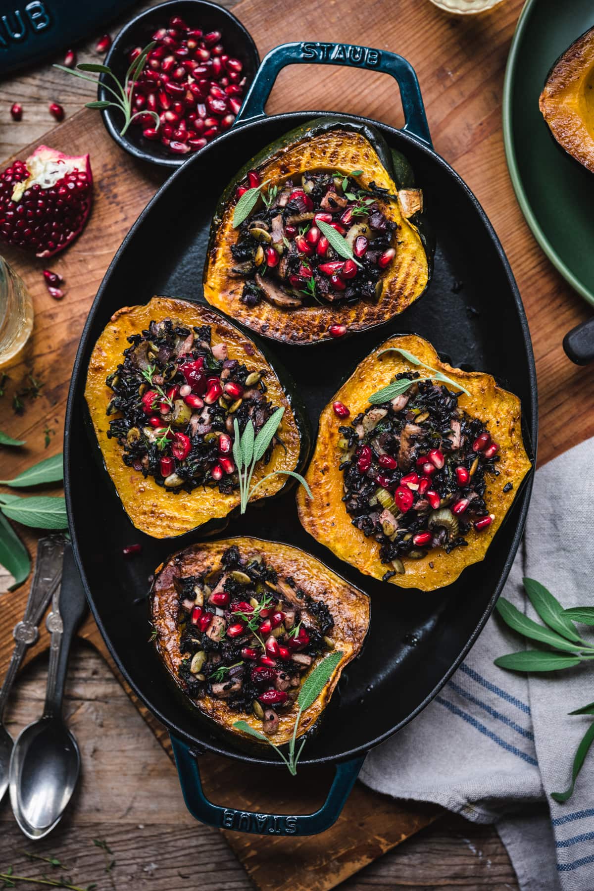 overhead view of vegan stuffed acorn squash with black rice, mushrooms and pomegranate seeds on top.