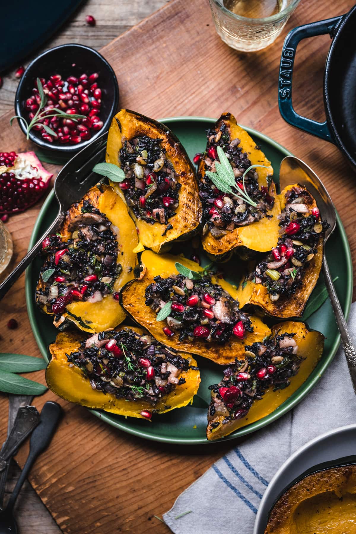 overhead view of slices of vegan stuffed acorn squash with black rice, mushrooms and pomegranate seeds on top.