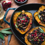 overhead view of slices of vegan stuffed acorn squash with black rice, mushrooms and pomegranate seeds on top.