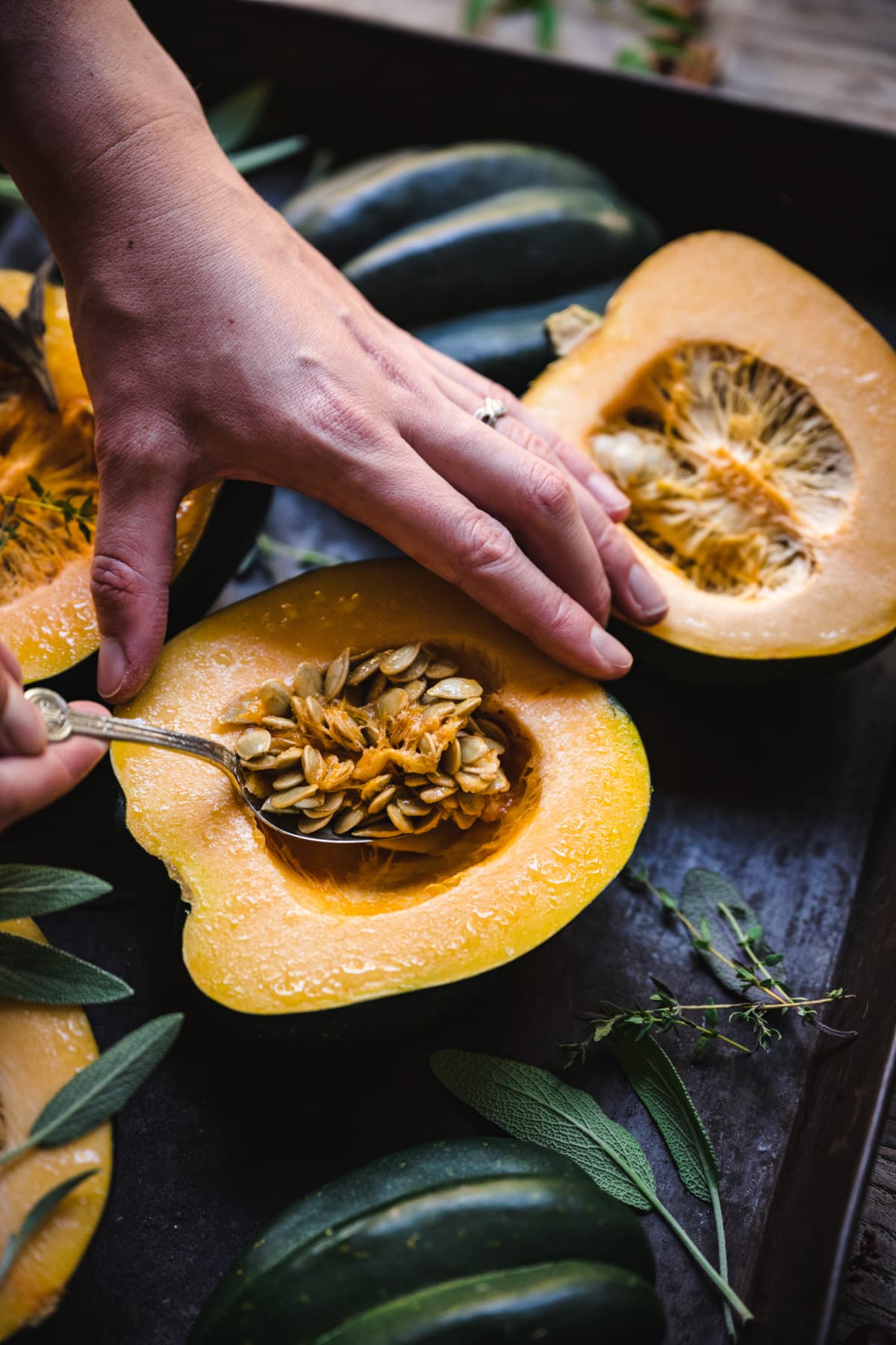 scooping seeds out of a half of an acorn squash.