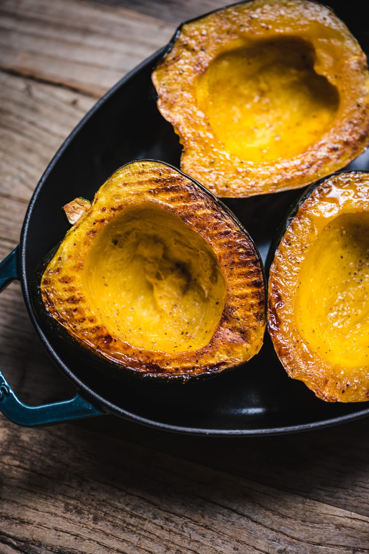 side view of roasted acorn squash half in a pan.