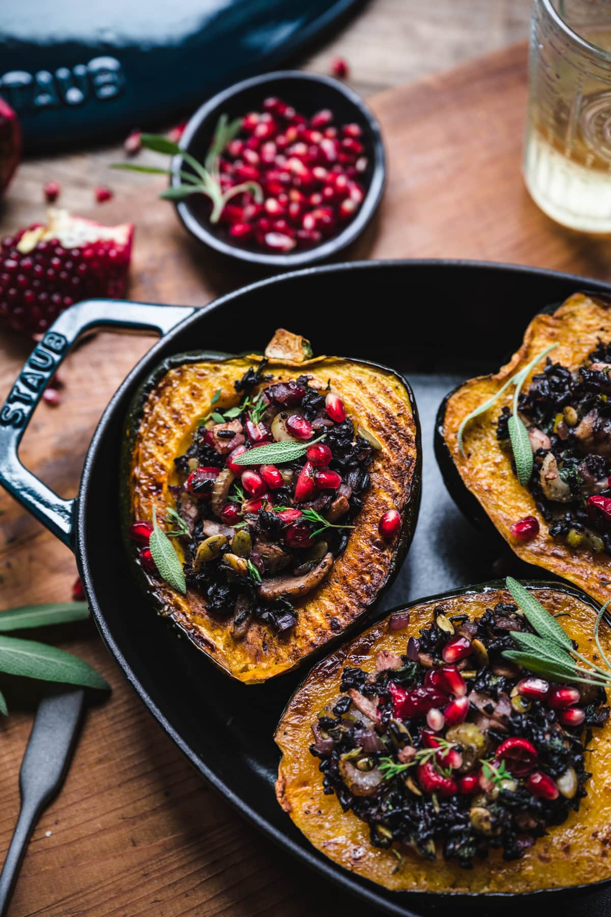 overhead view of vegan stuffed acorn squash with black rice, mushrooms and pomegranate seeds on top.