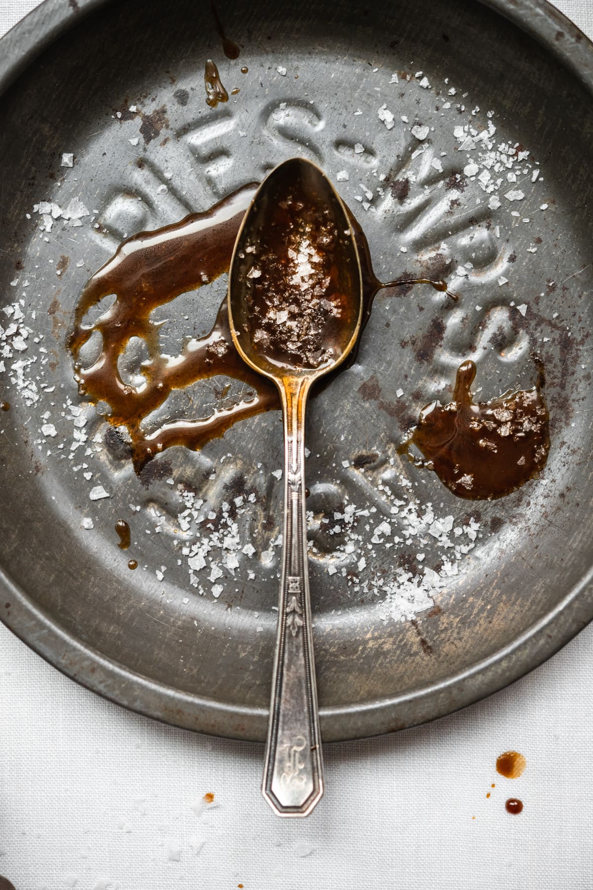 overhead view of vegan salted caramel on an antique spoon with flaky salt on top.