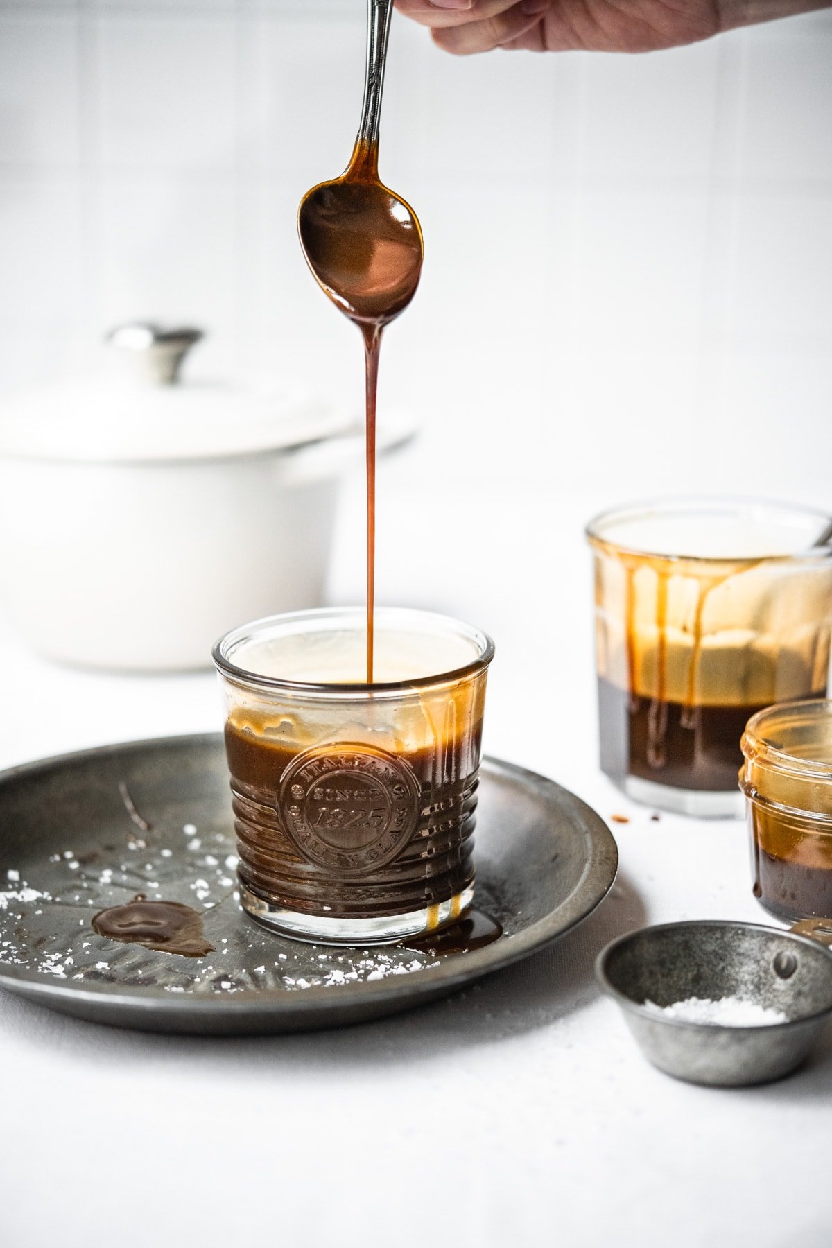 side view of person drizzling caramel sauce into a jar. 