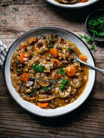 overhead view of vegan wild rice mushroom soup in a bowl on wood table.