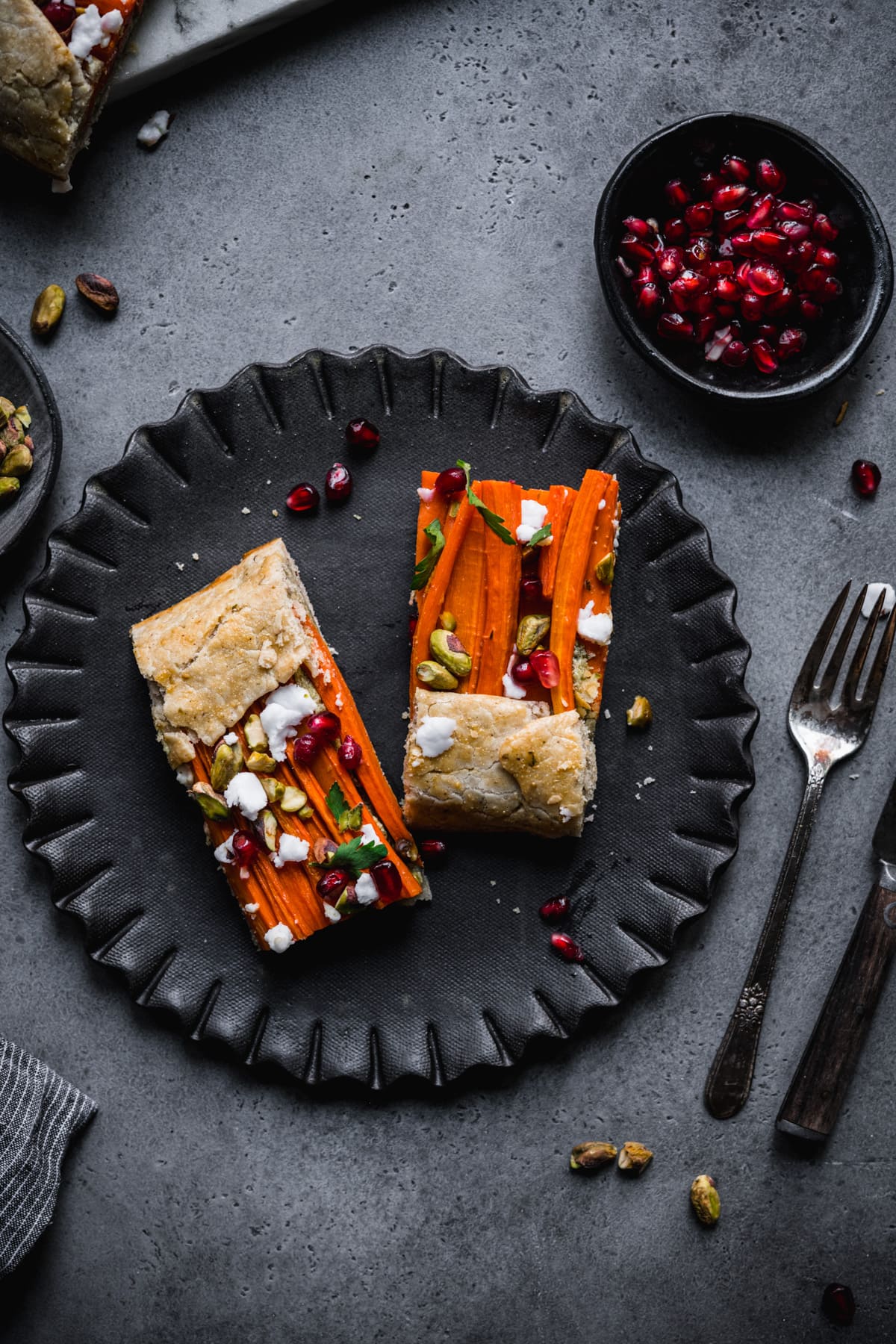 close up view of two slices of carrot tart on a black plate. 