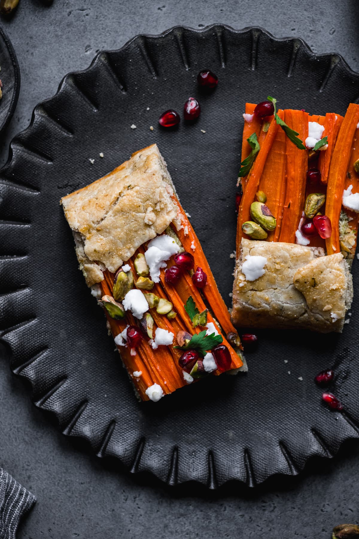 close up view of two slices of carrot tart on a black plate. 