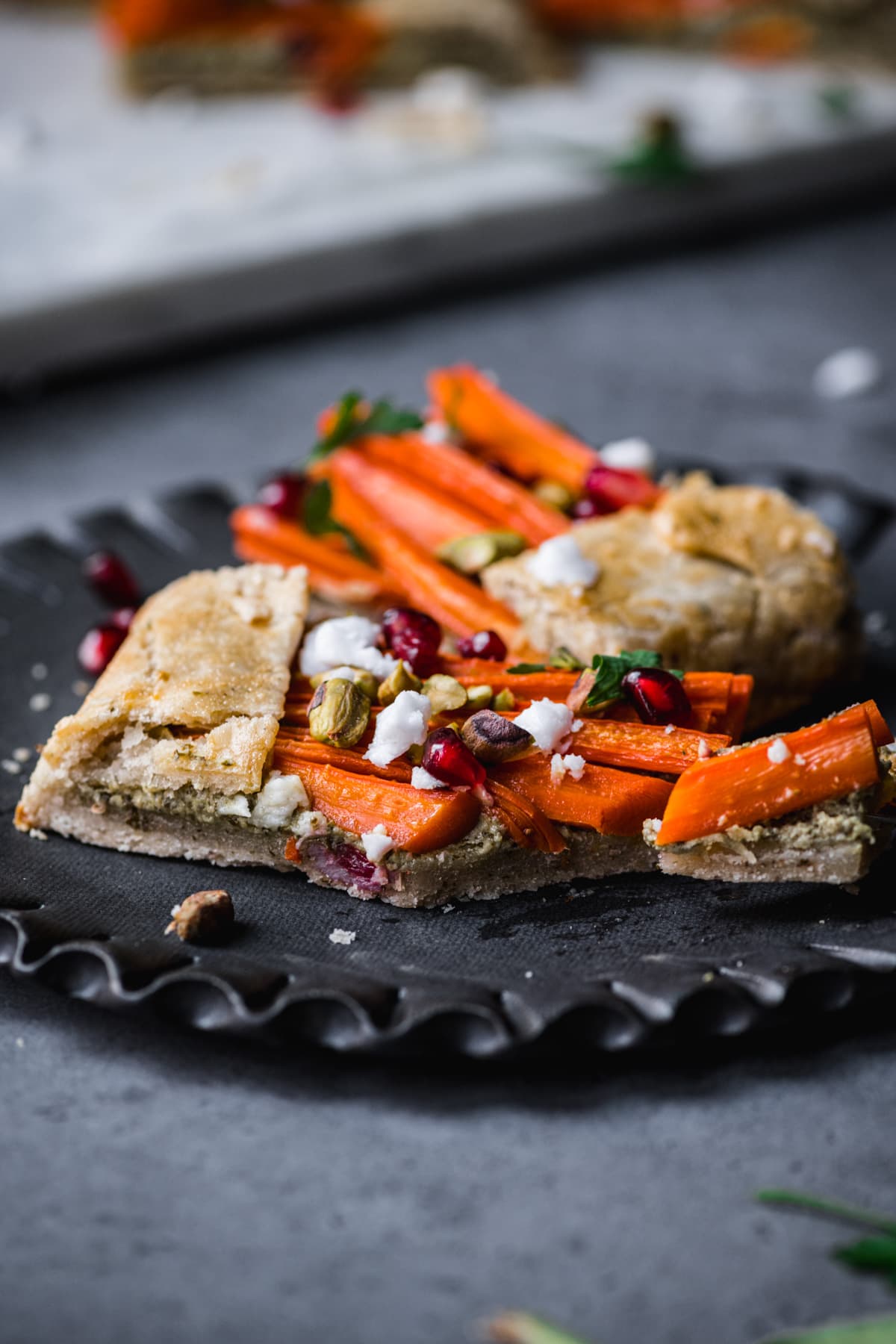 side view of slice of vegan carrot tart on a plate. 