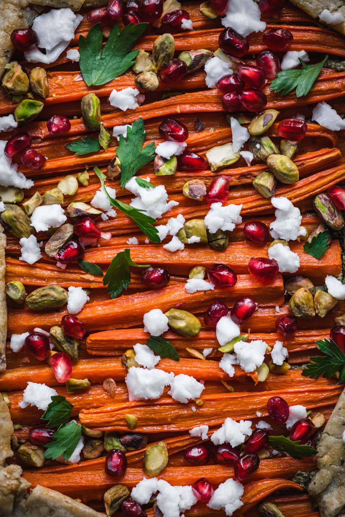 overhead view of vegan and gluten free carrot tart with pomegranate, pesto and pistachios.