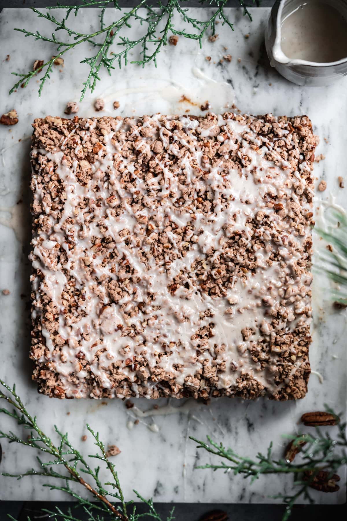 close up overhead view of gingerbread coffee cake with pecan streusel and vanilla glaze. 