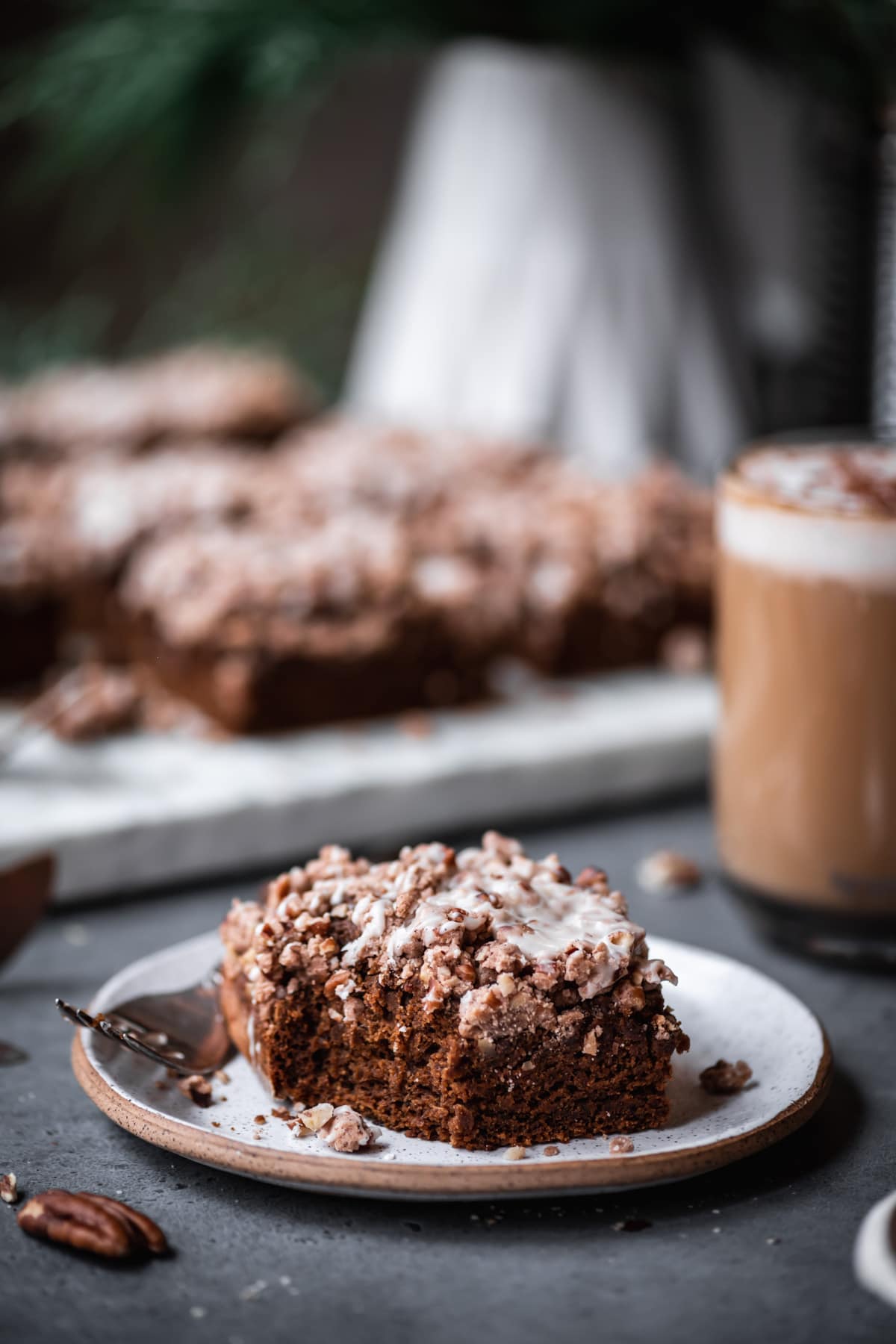 close up view of vegan gingerbread coffee cake slice on a small ceramic plate with bite taken out. 