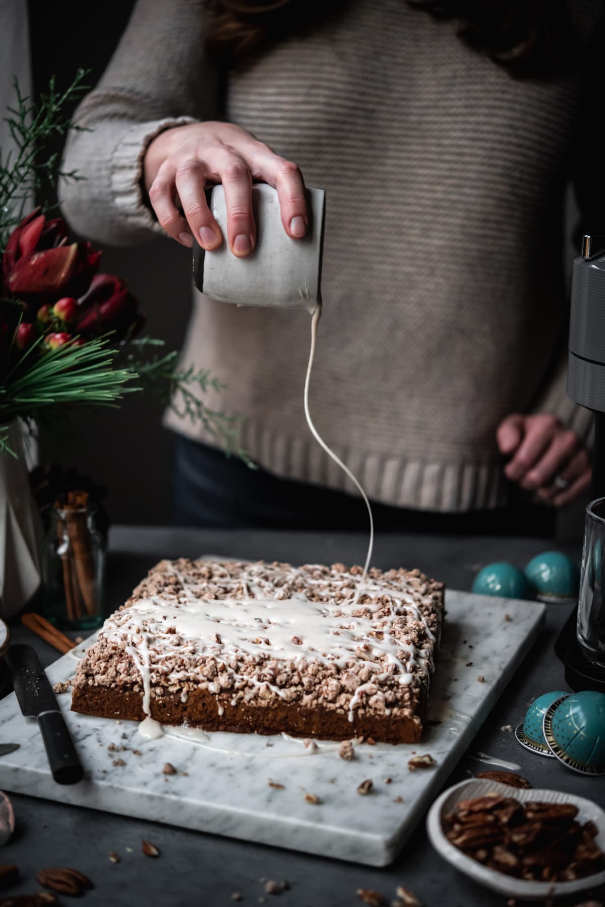 person drizzling vanilla glaze onto coffee cake.