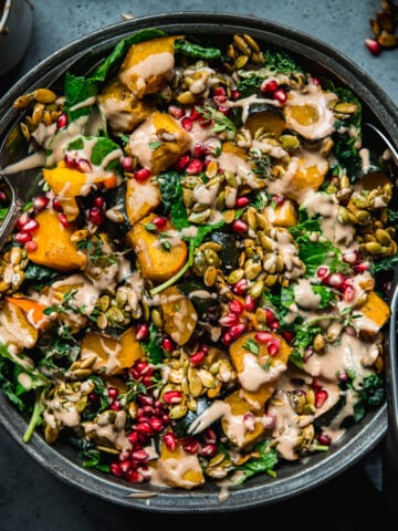 overhead view of roasted acorn squash salad with pumpkin seed brittle and tahini dressing.