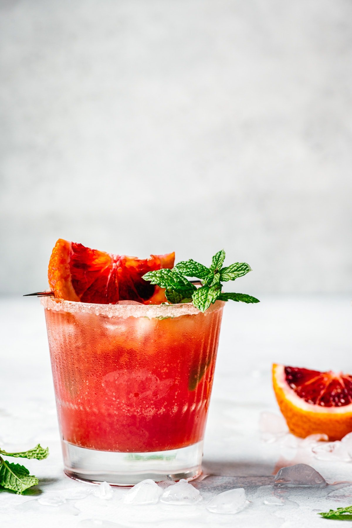 side view of blood orange kombucha margarita garnished with blood orange slice and fresh lime.