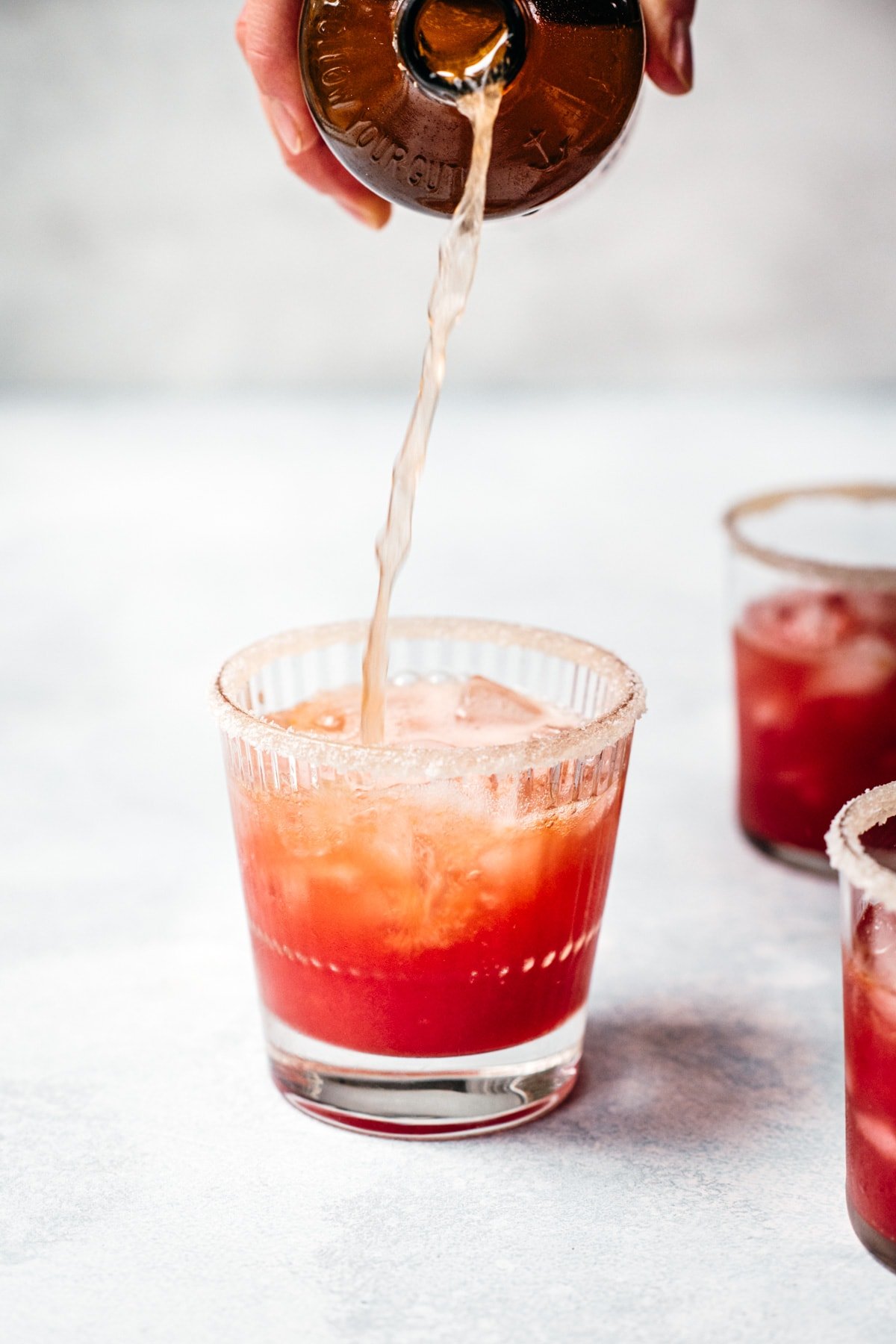 pouring kombucha into a blood orange margarita. 