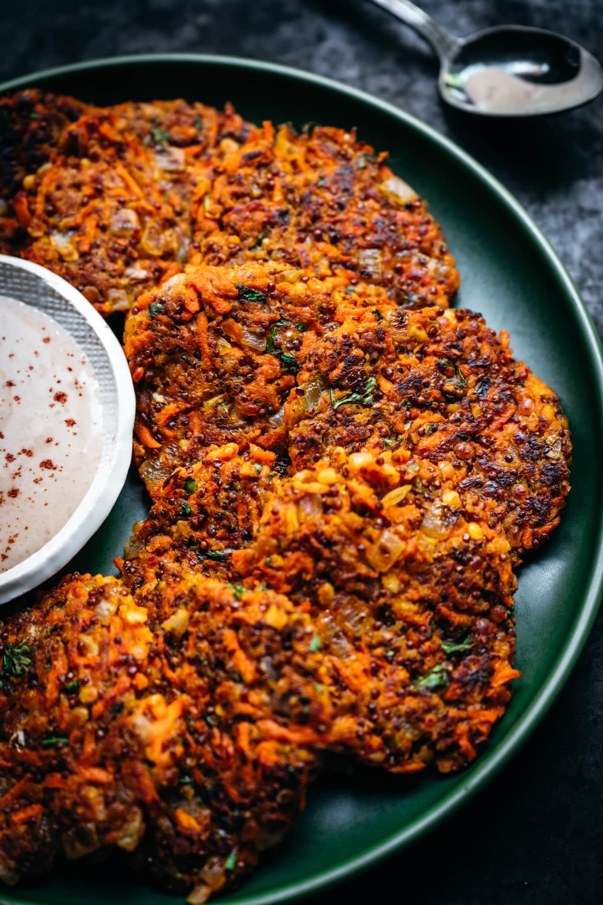 close up view of carrot fritters on a green plate. 