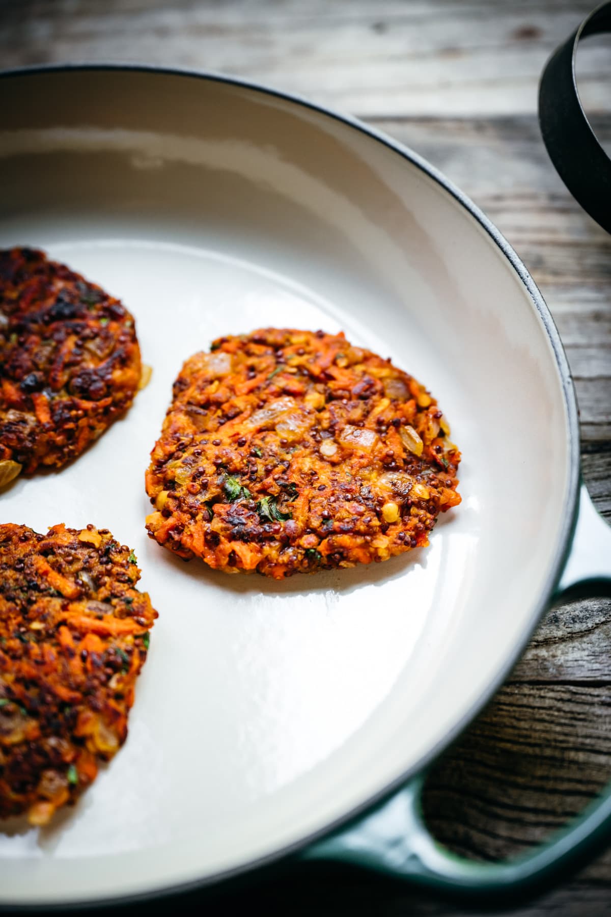 side view of carrot quinoa fritter in a pan.