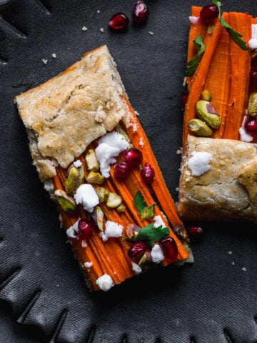 close up view of two slices of carrot tart on a black plate.