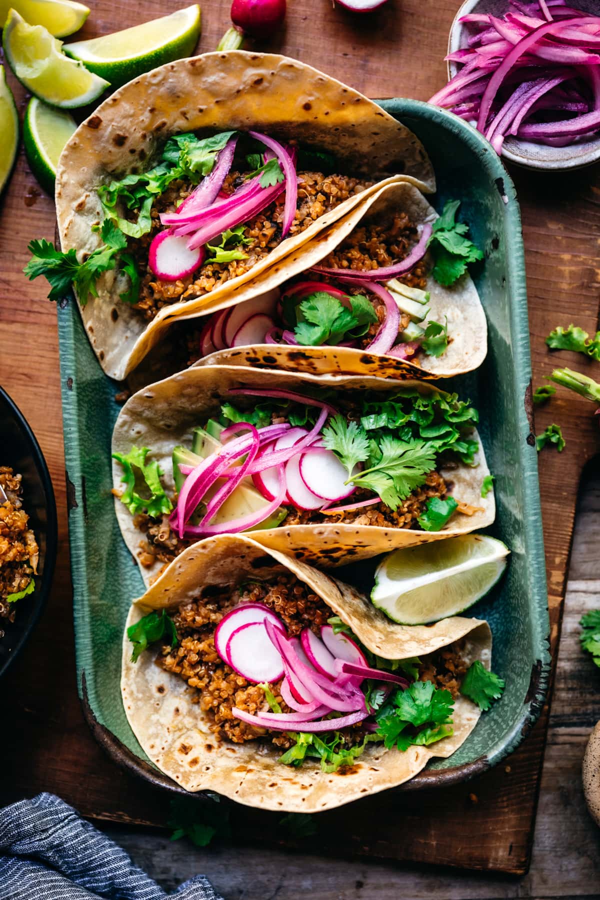 overhead view of vegan tacos in blue pan with pickled onions and avocado. 