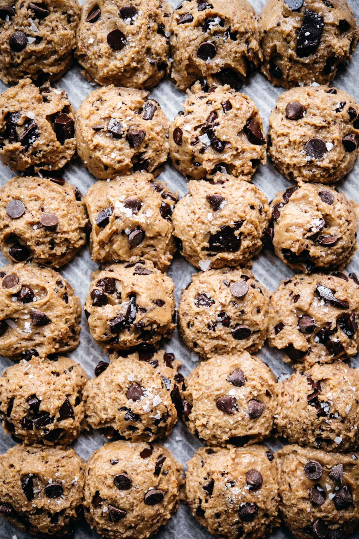 overhead view of vegan and gluten free chocolate chip cookies dough balls on parchment paper. 