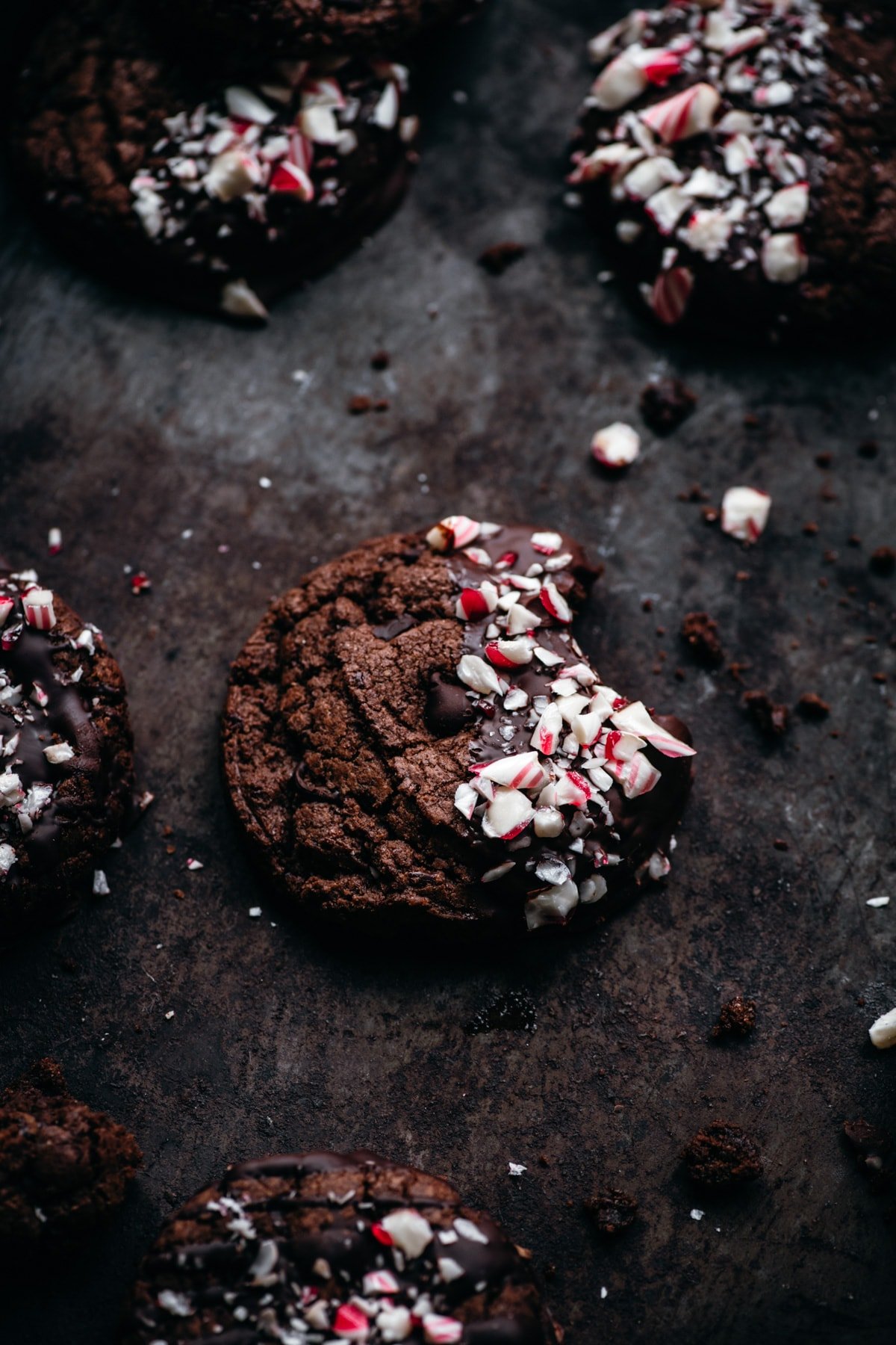 close up view of double chocolate peppermint cookie on baking sheet with bite taken out.