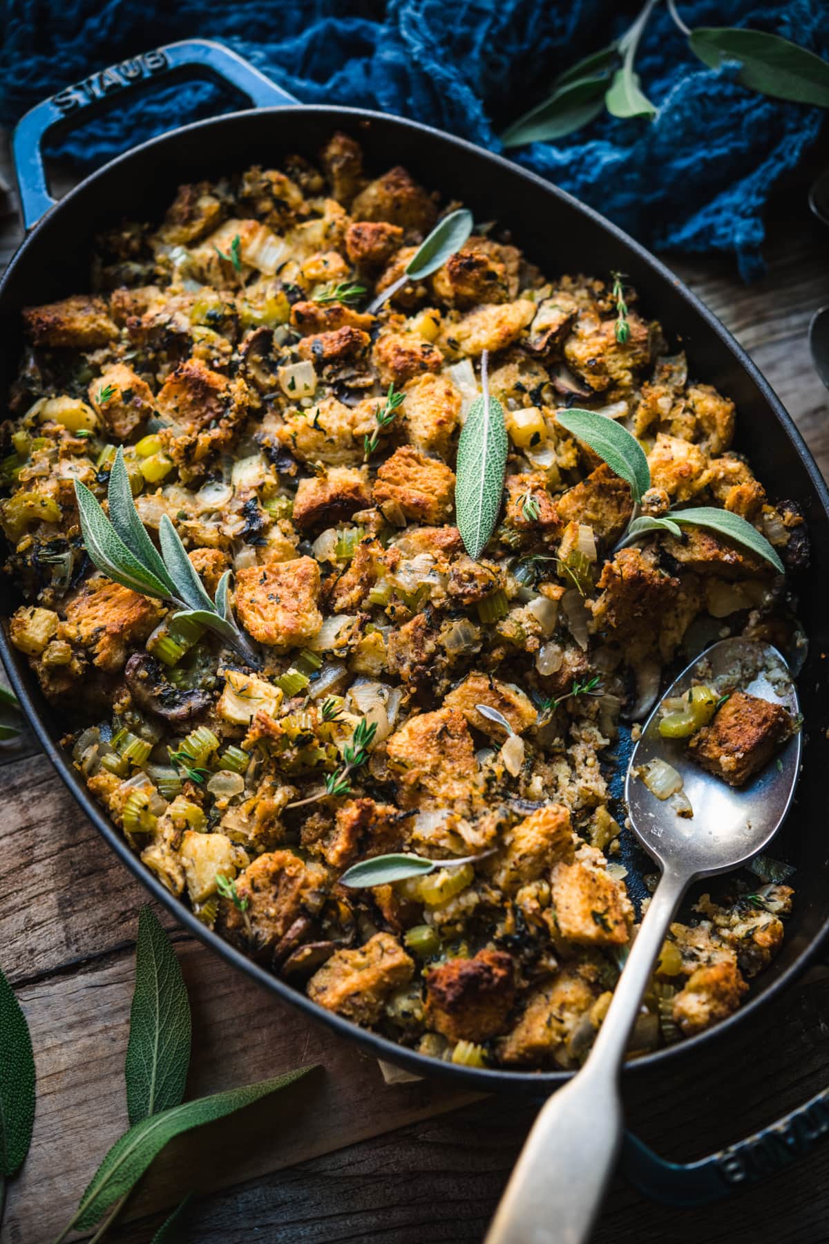 side view of gluten free vegan stuffing in an oval pan with serving spoon. 